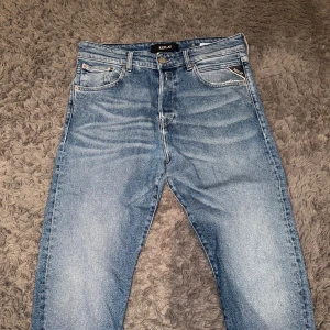 Blå jeans slim fit från Replay - Snygga blå jeans från Replay med klassisk femficksdesign och en läderpatch baktill. Jeansen har en slim passform och är perfekta för en avslappnad stil. De har en dragkedja och knapp framtill. Riktigt feta och i princip helt oanvända. Först till kvarn!!                                                   L25 W31