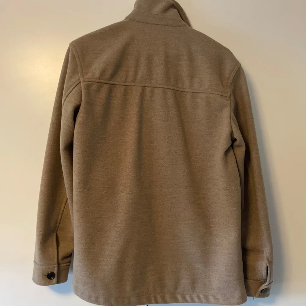 Säljer en stilren beige overshirt från Zara med knappar framtill och två stora bröstfickor. Perfekt för lager-på-lager-stil. Den har långa ärmar och en klassisk krage.. Takit.