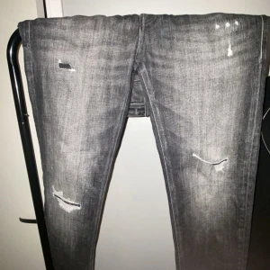Grå jeans med slitningar - Snygga grå jeans med coola slitningar på framsidan. De har en klassisk femficksdesign och en modern tvättad look. Perfekta för en avslappnad stil. Jeansen är köpta på Jack & Jones storlek 28/32