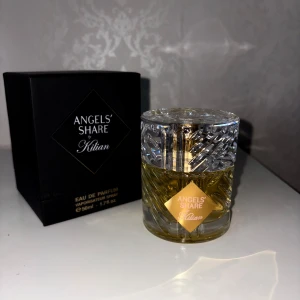 Angels' Share Eau de Parfum  - Säljer en exklusiv Angels' Share Eau de Parfum från Kilian. Flaskan är elegant med ett kristalliknande mönster och en gyllene vätska inuti. Förpackningen är stilren och svart med guldiga detaljer. Perfekt för den som älskar lyxiga dofter.OBS!  45 ML 