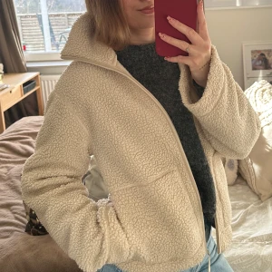 Ljusbeige pilejacka - Mysig beige teddyjacka med dragkedja framtill. Jackan har en hög krage och långa ärmar, perfekt till våren. Populär och slutsåld på H&M. den är i helt nyskick då jag har två stycken! :)