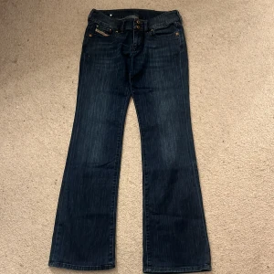 Mörkblå jeans med bootcut - Snygga mörkblå jeans från Diesel med bootcut-stil. De har dekorativa nitar vid fickorna och en klassisk femficksdesign. Perfekta för en avslappnad look.