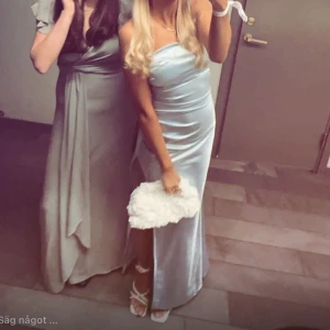 Satinklänning - Elegant ljusblå klänning i satin med en smickrande slits. Perfekt för en somrig fest eller bal. Klänningen har en figurnära passform som framhäver silhuetten. Den är uppsydd.