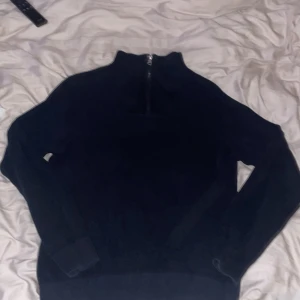 Svart tröja med halfzip från Kappahl - Säljer en svart tröja från Kappahl med dragkedja vid halsen. Tröjan har en ribbad struktur och långa ärmar, perfekt för kyligare dagar. Enkel och stilren design som passar till det mesta.