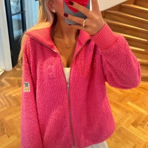 Rosa teddyjacka med dragkedja - Säljer en supermjuk och gosig rosa teddyjacka med dragkedja. Jackan har långa ärmar och en liten patch på ärmen. Perfekt för att hålla sig varm och stilren under kyliga dagar. 💖 passsr både s o m och är helt unik ❤️❤️