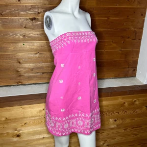 Rosa axelbandslös klänning med broderi - Charmig rosa axelbandslös klänning med vackra vita broderier och snörning i ryggen. Perfekt för sommarens varma dagar. Klänningen har en kort längd och en söt detalj med snörning som ger en unik touch. Saknar storlekslapp, men jag uppskattar att de här storlek S/M