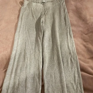 Grå randiga byxor - Snygga grå byxor med ränder och en loose passform. Perfekta för en avslappnad stil. Byxorna har en hög midja och är tillverkade i ett mjukt material som ger en bekväm känsla.