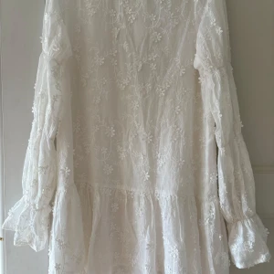 Vit blommig klänning från NA-KD - Jättefin populär och eftertraktad vit  klänning ifrån NA-KD! Perfekt för student, skolavslutning, konfirmation eller liknande! Jättefin design med öppen rygg där bak! Storlek 34! Endast använd 2 gånger💕 pris kan diskuteras och kom med frågor! 💕