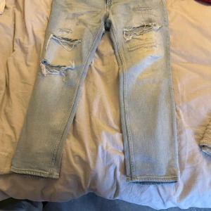 Ljusa jeans från H&M - Säljer ett par ljusa skinny fit jeans från H&M. De har en trendig slitning på framsidan och är perfekta för en avslappnad stil. Passar bra till sneakers eller boots.