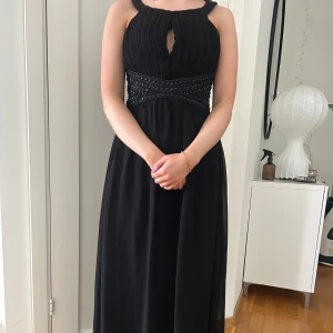 Svart balklänning med pärldetaljer - Elegant svart långklänning med vackra pärldetaljer i midjan. Perfekt för bal eller annat event! Helt ny i storlek 36, säljer samma klänning i ljusrosa!!!