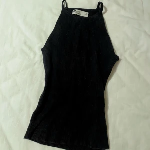 Svart ribbad topp från FB Sister Knitwear - Snygg svart ribbad linnetopp från FB Sister Knitwear. Smala axelband och en enkel design, perfekt basic att ha i garderoben. Passar bra till både jeans och kjol.