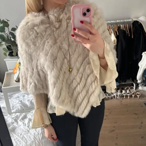 Beige/vit pälsponcho - Ljus beige poncho i fuskpäls. Superfin att ha över en blus eller tröja. Använd en gång🥰