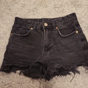 Svarta jeansshorts med fransar - Snygga svarta jeansshorts med fransiga kanter och slitna detaljer.  De har en hög midja och klassisk femficksdesign. Säljer då dom (som ni ser på bild nr 2) har blivit för små