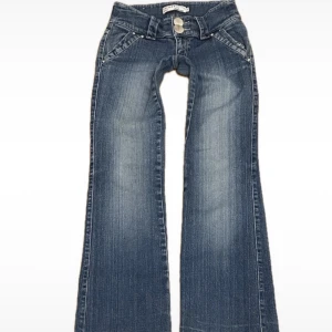 Blå bootcut jeans från Ich - Snygga blå bootcut jeans från Ich med dubbla knappar i midjan. De har en klassisk femficksdesign och en lätt slitning för en trendig look. Perfekta för en avslappnad stil.