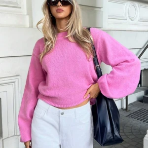 Rosa stickad tröja med öppen rygg - Säljer en snygg rosa stickad tröja med en unik öppen rygg och knytband. Tröjan har långa ärmar och en avslappnad passform, perfekt för en trendig look. Passar bra till både jeans och kjol. Perfekt för vår och sommar!