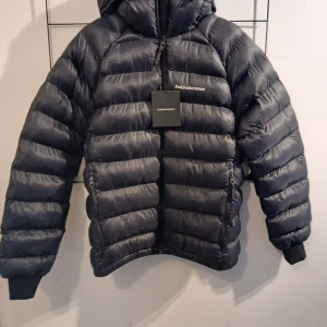 Svart dunjacka från Peak Performance M - Snygg svart dunjacka från Peak Performance med huva och dragkedja. Jackan är aldrig använd och köptes i slutet på november. Beställde två och glömde skicka tillbaka den dom inte passade. Storlek M man 