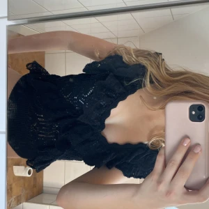 Svart spetsblus från Zara - Säljer en elegant svart spetsblus från Zara med vackra volangdetaljer. Blusen har en fin struktur och är perfekt för att ge en stilfull touch till din outfit. Passar bra till både jeans och kjol.