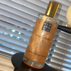 Rituals Shimmering Body Oil - Lyxig kroppsolja från Rituals med skimrande effekt. Perfekt för att ge huden en glittrande och återfuktad look. Kommer i en elegant flaska med guldlock.