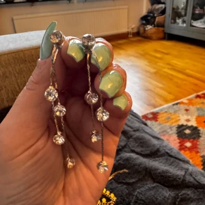 Silverfärgade örhängen med pärlor - Säljer ett par snygga silverfärgade örhängen med hängande pärlor. De har en elegant design med flera små pärlor som hänger i olika längder. Perfekta för att piffa upp vilken outfit som helst!