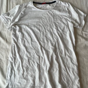 Vit t-shirt från Race Marine - Säljer en vit t-shirt från Race Marine i storlek S. T-shirten är gjord av bomull och har en bröstficka på vänster sida. Den har korta ärmar och en normal passform. Perfekt för sommaren eller som en baströja i garderoben. Lite övertvättad och småknottrig, främst baksida. Frågor? Skriv!