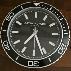 RAYMOND WEIL Geneve väggklocka  - Väggklocka av märket Raymond weil Geneve i bra skick. Fungerar som den ska. Lyser i mörkret och är ganska snygg design 👍  Är ganska sällsynt klocka