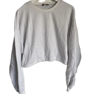 Croppad sweatshirt med tryck bak - Vit croppas sweatshirt med band i midjan att dra åt. Har tryck på baksidan