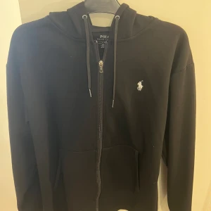 Ralph Lauren zip-hoodie - Säljer en svart zip- hoodie från Ralph Lauren. Väldigt bekväm men för stor för mig. Skick 10/10. Storlek: L passar även M
