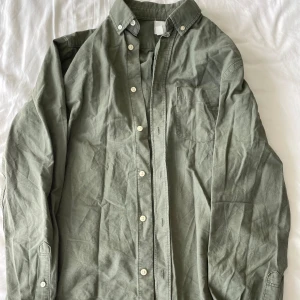 Grön långärmad skjorta från H&M - Säljer en grön långärmad skjorta från H&M i storlek S. Skjortan har en klassisk krage med knappar och en bröstficka på vänster sida. Perfekt för både vardag och fest! Frågor? Skriv!