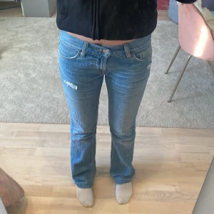 Lågmidjade jeans  - Snygga blå jeans från Fornarina med slitna detaljer och bootcut-stil. Har även 2 knappar så går att spänna in/ut om man vill. Passar mig perfekt i längd (är 160) Midjemått 36 cm (mätt från sida till sida)