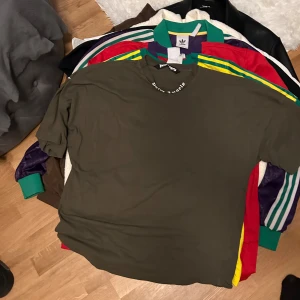 Olivgrön t-shirt från Palm Angels - Säljer en olivgrön t-shirt från Palm Angels med stort vitt tryck på framsidan. T-shirten har en avslappnad passform och är perfekt för en casual look. Den har korta ärmar och en rund halsringning.