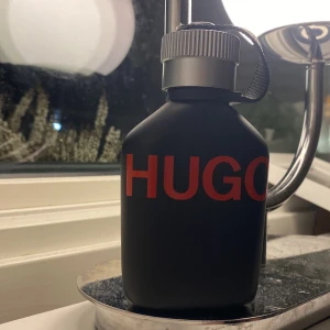 Svart parfymflaska från Hugo Boss - Säljer en stilren svart parfymflaska från Hugo Boss med röd text.  Mer än halva kvar 75ml 