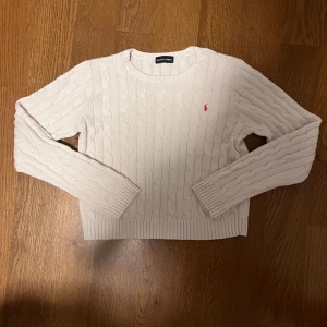 Vit Ralph Lauren kabelstickad dam - Vit Ralph Lauren kabelstickad dam, röd/rosa ponnylogga  🌟Riktigt fint skick, endast använd ett par gånger. Det enda negativa är att storleksetiketten saknas  🐑100% bomull, riktigt bekvämt och stretchigt material  📬Jag skickar inom samma eller nästa dag efter köpet  📏Storlek XS för dam, passformen har en kortare och avskuren topp runt magen. Se mått nedan  📐37cm axelbredd, 44cm full längd, 52cm ärmlängd (alla mätt på plan mark)  😊 Ställ gärna frågor  #ralphlauren #poloralphlauren #zip #zipup #trö