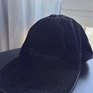 Svart keps från Champion - Snygg svart keps från Champion i mjukt material. Kepsen har justerbart spänne baktill för perfekt passform. Perfekt för en avslappnad stil.