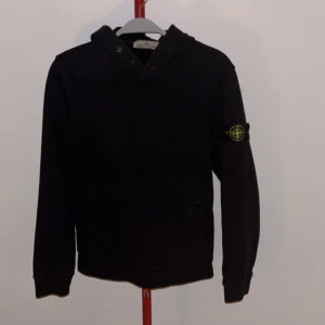 Svart hoodie från Stone Island - Säljer en stilren svart hoodie från Stone Island med deras ikoniska märke på ärmen. Tröjan har en klassisk design med långa ärmar och en bekväm passform. Perfekt för en casual look. Pris kan såklart diskuteras