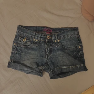 Lågmidjade jeansshorts  - Snygga jeansshorts från Urban Heart med  detaljer och knappstängning. De har en klassisk blå denimfärg och är perfekta för en avslappnad stil. Shortsen har fem fickor och en liten läderpatch med logga baktill 💞