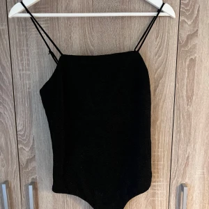 Svart glittrig body från Bik Bok - Snygg svart body från Bik Bok med glittrigt material och smala justerbara axelband.