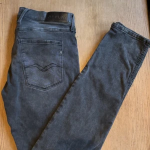 Gråa Replay anbass slim fit - Snygga grå jeans från Replay. De har en diskret logga på bakfickan och en bekväm passform. Perfekta för en stilren look. Dom är i W34 och längd 34 