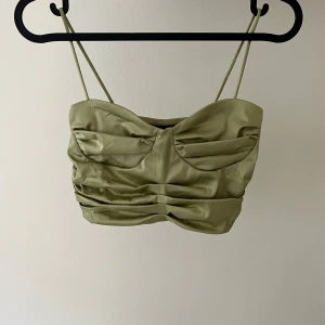 Olivgrön satinlinnetopp från Gina Tricot - Snygg olivgrön linnetopp i satin från Gina Tricot med smala axelband och rynkade detaljer framtill. 