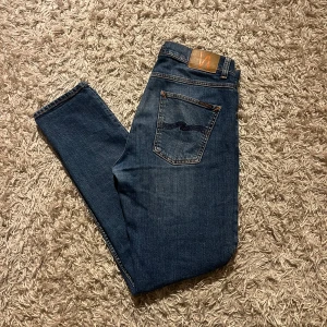 Nudie Jeans modell Lean Dean  - Snygga blå jeans från Nudie Jeans med klassisk femficksdesign och orange sömmar. Jeansen har en slim/straight passform och är tillverkade i bomull. Perfekta för en avslappnad stil. Modell Lean Dean strlk 32/32, inga märkvärda anmärkningar. Fraktas antigen samma dag som köp eller dagen därpå🙌💯