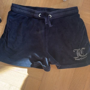 Svarta shorts från Juicy Couture - Marinblå shorts från Juicy Couture i mjukt material. De har en bekväm passform med snörning i midjan och en bakficka. Perfekta för en avslappnad stil. 