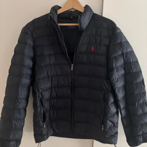 Mörkblå dunjacka från Polo Ralph Lauren - Säljer en mörkblå jacka från det eftertraktade märket Ralph lauren. Storleken är M men skulle säga att det passar S. Nypris är runt ca 4000kr. Vid frågor hör av er! Pris inte hugget i sten!
