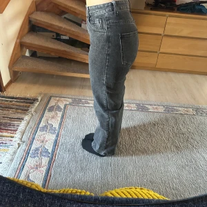 Grå jeans med hög midja - Snygga grå jeans med hög midja och rak passform. De har klassiska femficksdetaljer och en stilren look som passar till det mesta. Perfekta för dig som gillar en tidlös stil.