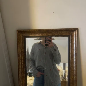 Randig skjorta från Lee - Säljer en stilren randig skjorta från Lee i svart och vit med röda broderade detaljer. Riktigt snygg men använder inte så mycket längre. Den är väldigt mjuk och skön i tyget, och lätt och avslappnad i passform. 