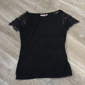 Svart spetsblus från KappAhl - Snygg svart blus från KappAhl i storlek XS. Blusen har korta ärmar och är tillverkad i ett vackert spetsmaterial💕
