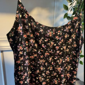 Blommig klänning från Forever 21 - Söt blommig klänning från Forever 21 i svart med små blommor i rosa och vita nyanser. Klänningen har en smickrande passform och är perfekt för varmare dagar. Den är ärmlös och har en lätt och luftig känsla med dragkedja för att få på sig den smidigt💗