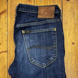 Mörkblå jeans från Lee - Snygga mörkblå jeans från Lee med klassisk femficksdesign och kontrasterande gul söm. Priset är inte hugget i sten!