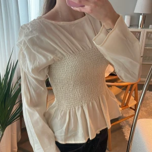 Beige blus med smockdetaljer - Beige blus med smockdetaljer över bysten och volang nedtill 🥰