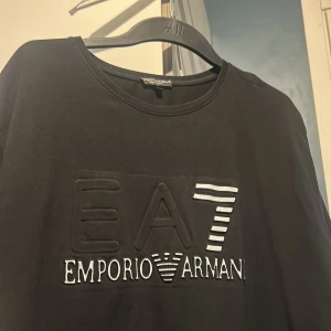 Svart tröja från Emporio Armani - Snygg svart tröja från Emporio Armani med EA7-logga på framsidan. Perfekt för en stilren look. Tillverkad i Italien.
