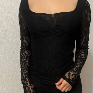 Svart spetsblus från BikBok - Snygg svart spetsblus från BikBok i storlek XS. Blusen har långa ärmar och ett elegant blommönster. Perfekt för en utekväll eller fest! 💃