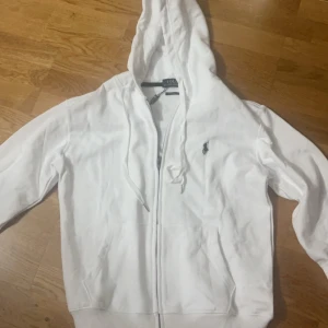 Polo Ralph Lauren Zip up hoodie vit - En populär vit polo zip up hoodie. Färgen vit och den är storlek M. Perfekt skick och anledningen till försäljningen är att den helt enkelt är för liten. Kom privat för fler bilder!